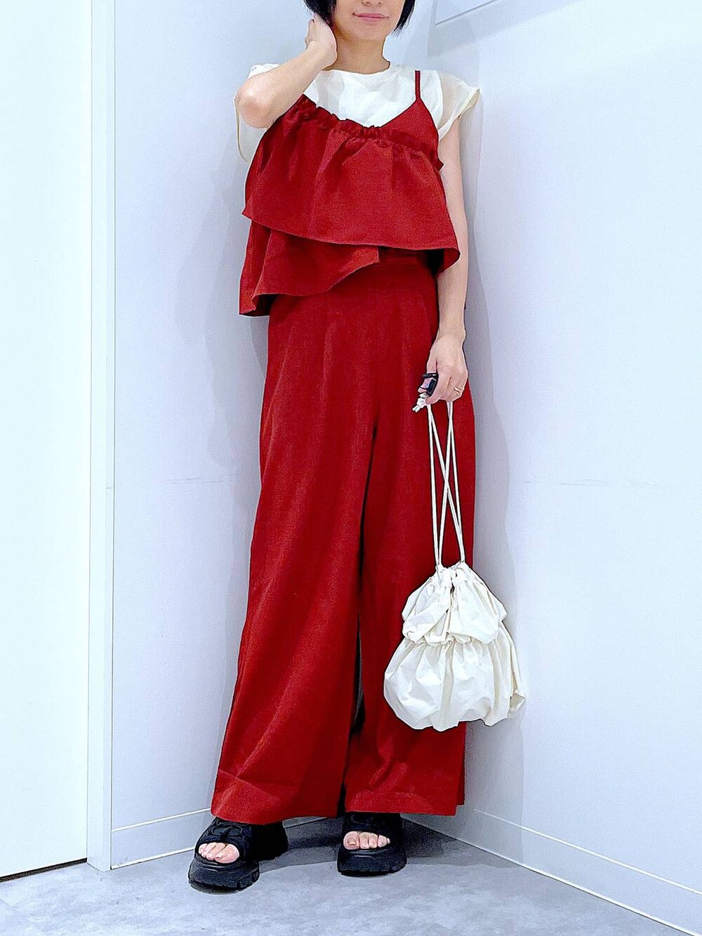 ブラック系のスニーカー、ホワイト系のショルダーバッグ、レッド系のつなぎ/オールインワンを着用したレディースの夏コーディネートの6枚目の写真