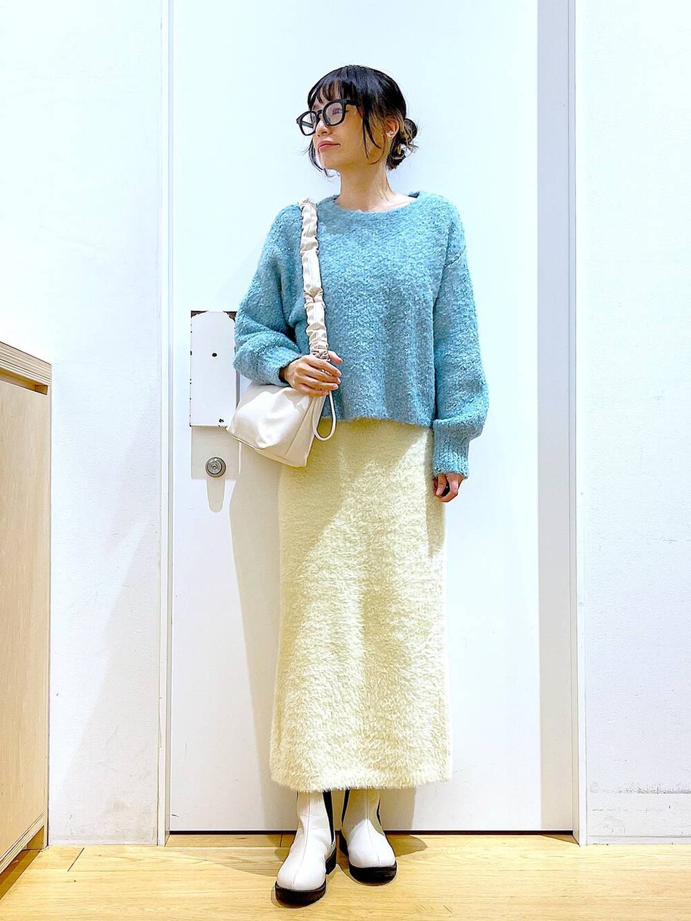 ホワイト系のショルダーバッグ、ベージュ系のブーツ、ホワイト系のスカートを着用したレディースの冬コーディネートの2枚目の写真