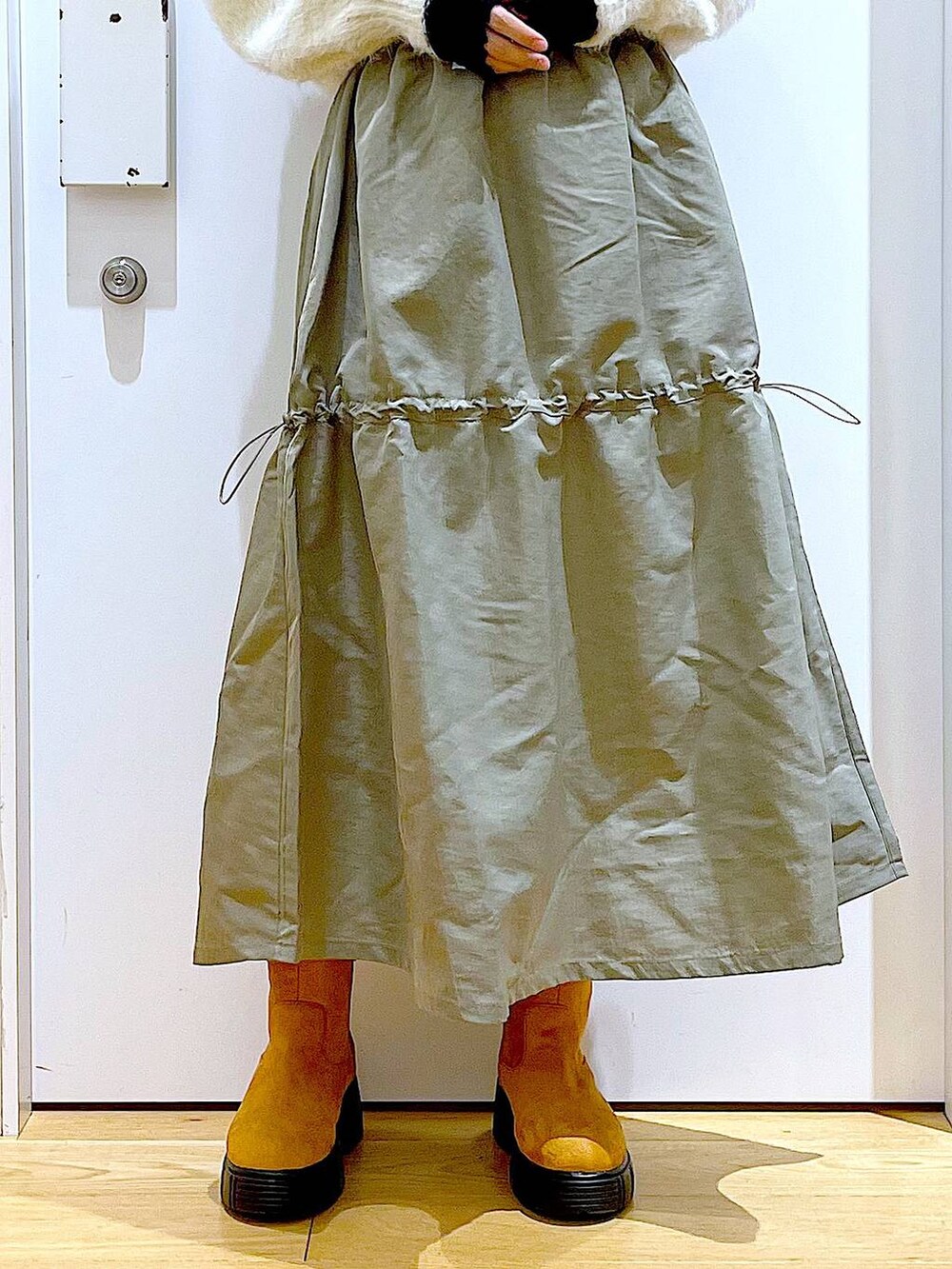 ベージュ系のショルダーバッグ、ベージュ系のブーツ、ベージュ系のニット/セーターを着用したレディースの冬コーディネートの8枚目の写真