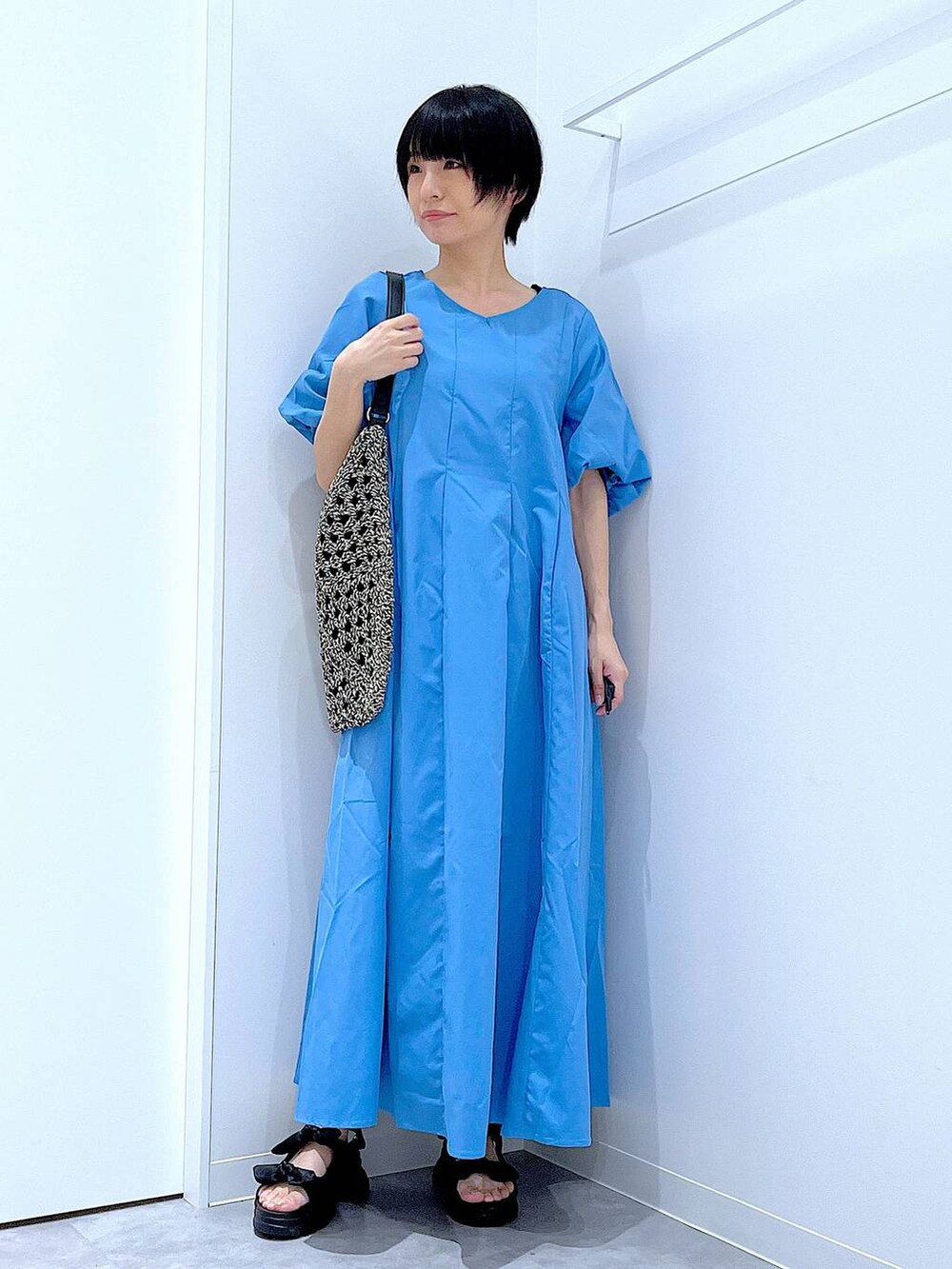 ブラック系のトートバッグ、ブラック系のサンダル、ブルー系のワンピースを着用したレディースの夏コーディネートの2枚目の写真