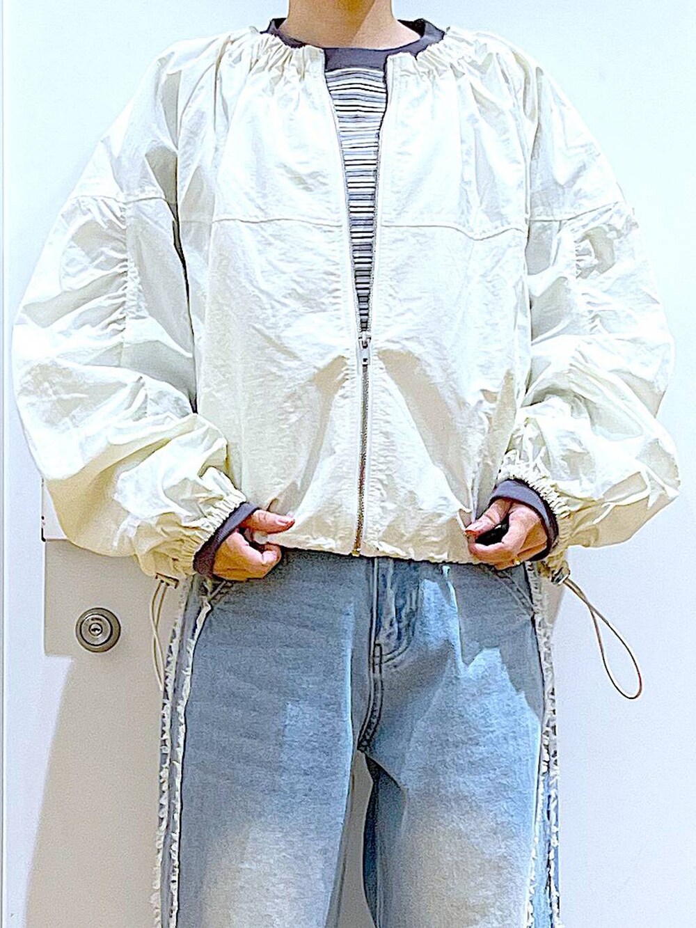 ホワイト系のスニーカー、ブルー系のデニムパンツ、ホワイト系のブルゾンを着用したレディースの春コーディネートの7枚目の写真