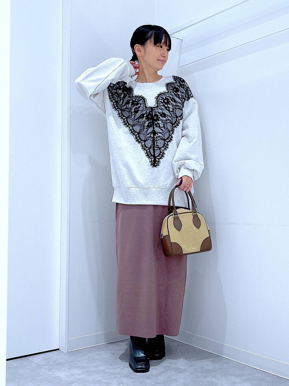 ベージュ系のハンドバッグ、ブラック系のブーツ、ベージュ系のスウェットを着用したレディースの秋コーディネートの2枚目の写真