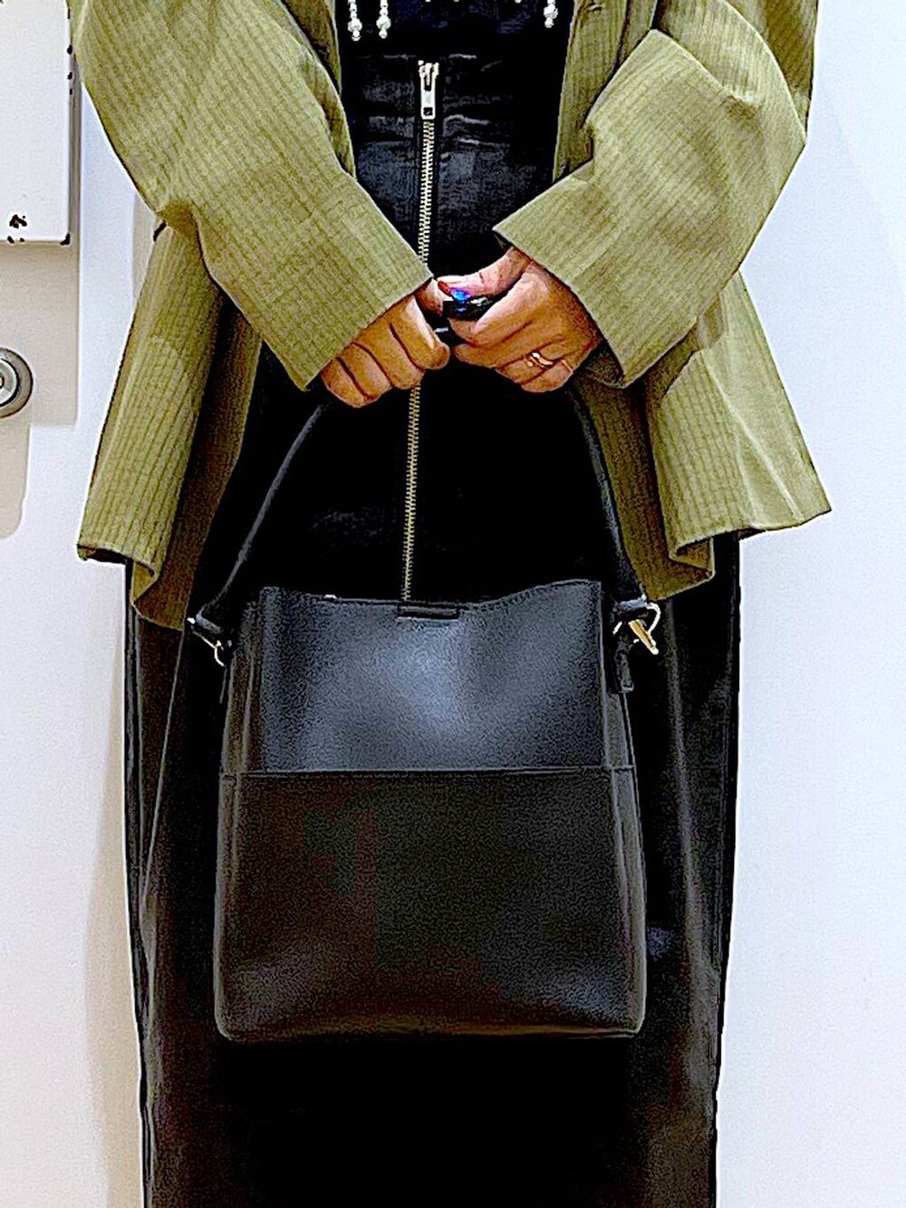 ホワイト系のベスト、ブラック系のスカート、ブラック系のショルダーバッグを着用したレディースの秋コーディネートの9枚目の写真