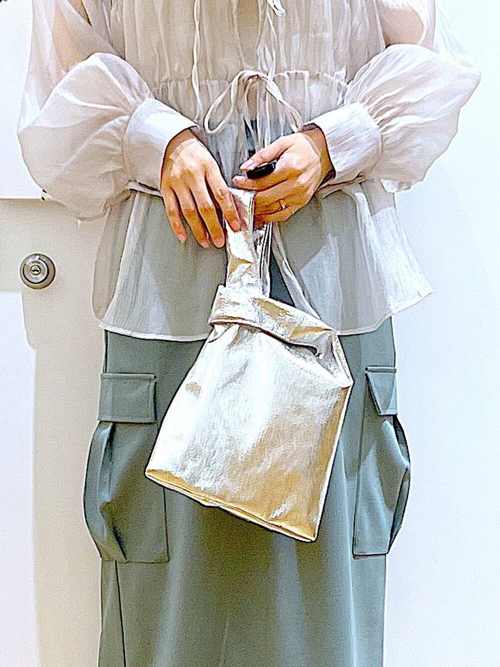 シルバー系のショルダーバッグ、グレー系のシャツ/ブラウス、ホワイト系のパンプスを着用したレディースの春コーディネートの9枚目の写真