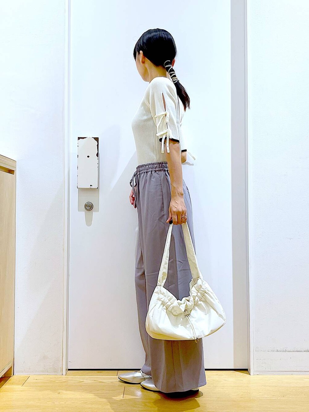 ホワイト系のハンドバッグ、グレー系のその他パンツ、シルバー系のパンプスを着用したレディースの秋コーディネートの3枚目の写真