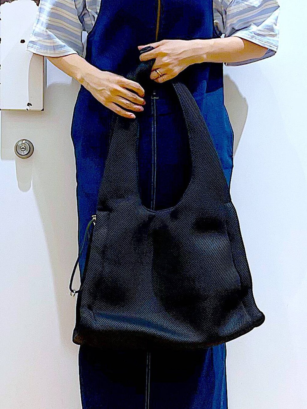 ホワイト系のパンプス、ブルー系のジャンパースカート、ブラック系のショルダーバッグを着用したレディースの夏コーディネートの9枚目の写真