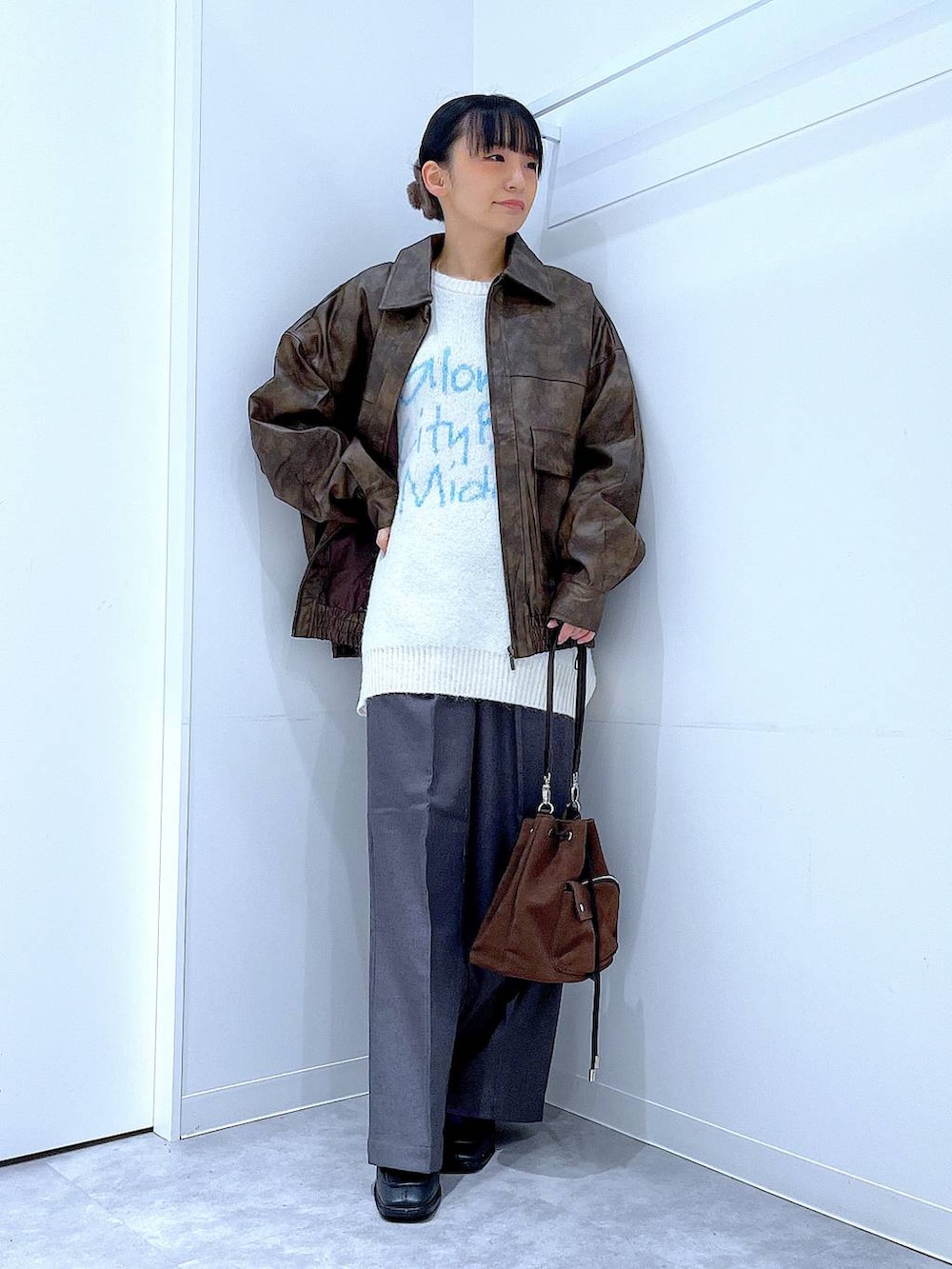 ブラウン系のブルゾン、ブラウン系のショルダーバッグ、ブラック系のブーツを着用したレディースの冬コーディネートの2枚目の写真