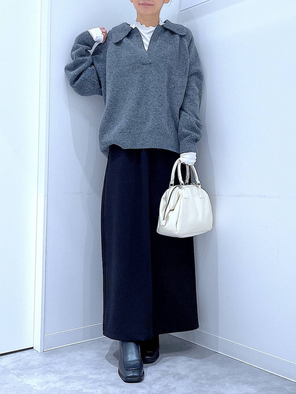 ブラック系のスカート、ブラック系のブーツ、ホワイト系のショルダーバッグを着用したレディースの冬コーディネートの6枚目の写真