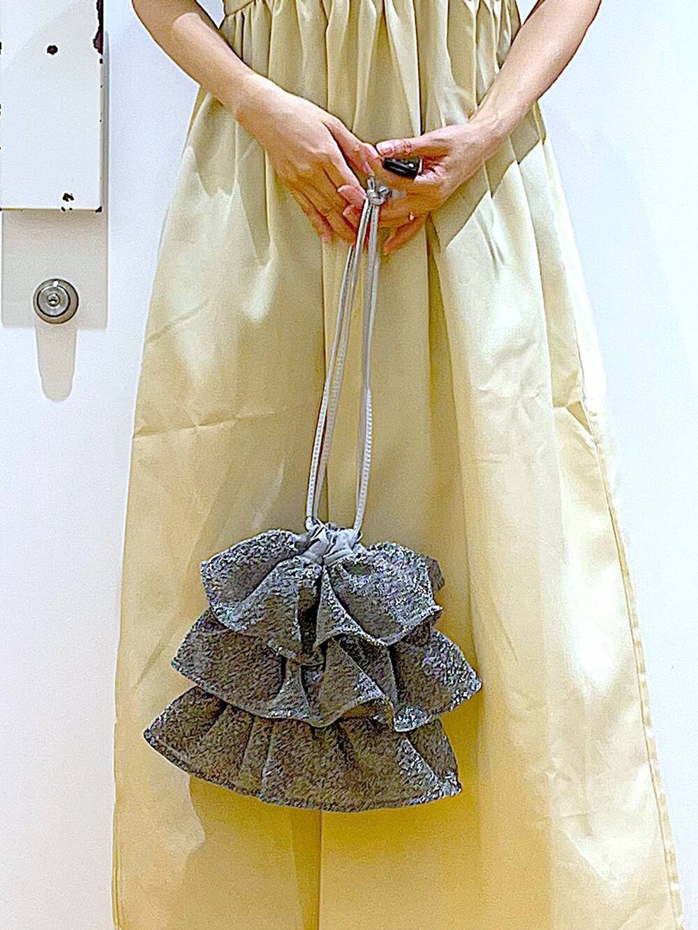 シルバー系のショルダーバッグ、シルバー系のサンダル、ブラック系のTシャツ/カットソーを着用したレディースの夏コーディネートの9枚目の写真