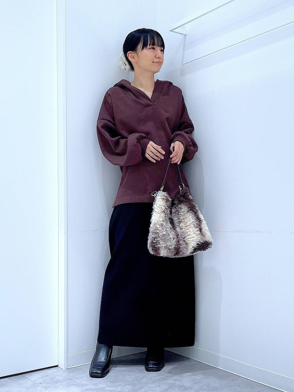 ブラック系のブーツ、ブラウン系のショルダーバッグ、ブラック系のスカートを着用したレディースの冬コーディネートの2枚目の写真