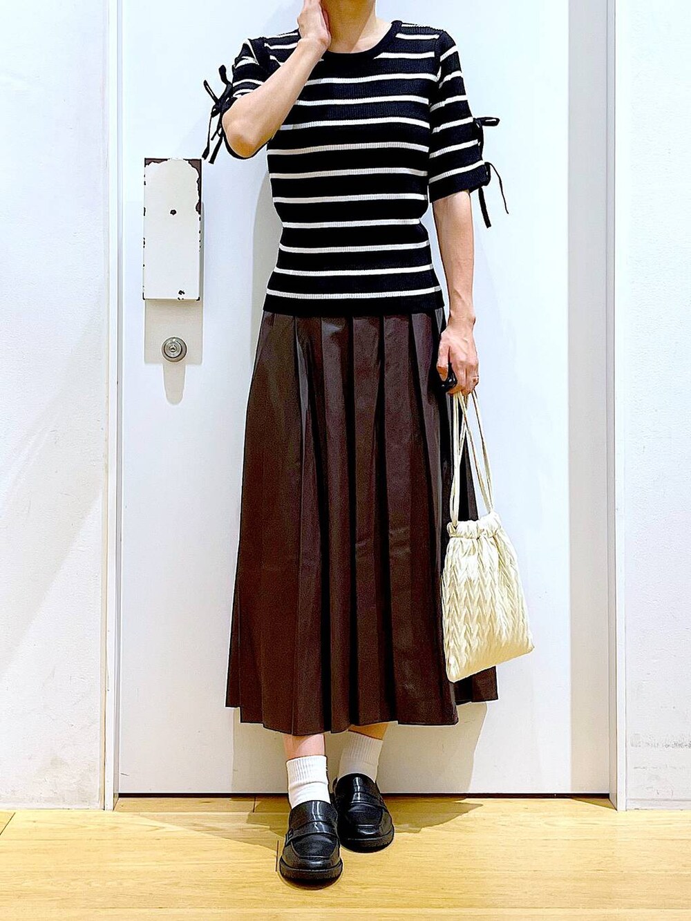 ホワイト系のショルダーバッグ、ブラック系のローファー、ブラック系のニット/セーターを着用したレディースの秋コーディネートの6枚目の写真