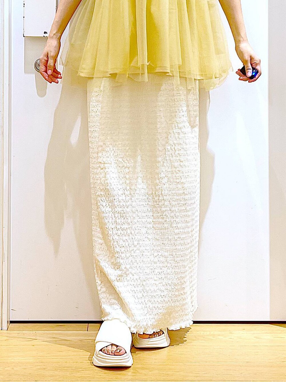 ホワイト系のサンダル、ベージュ系のスカート、イエロー系のTシャツ/カットソーを着用したレディースの夏コーディネートの8枚目の写真