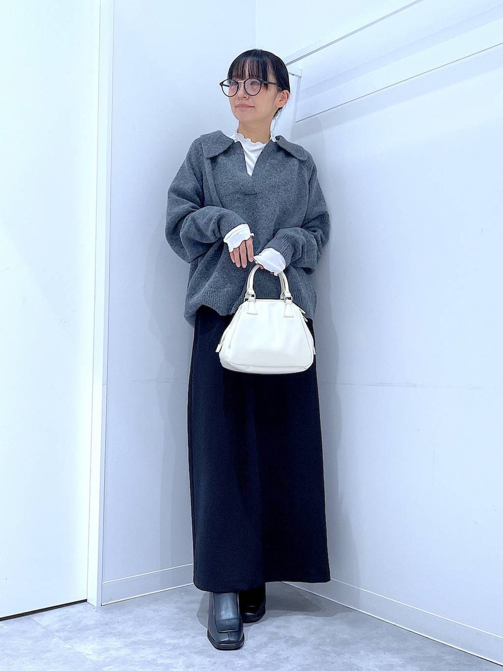 ブラック系のスカート、ブラック系のブーツ、ホワイト系のショルダーバッグを着用したレディースの冬コーディネートの2枚目の写真