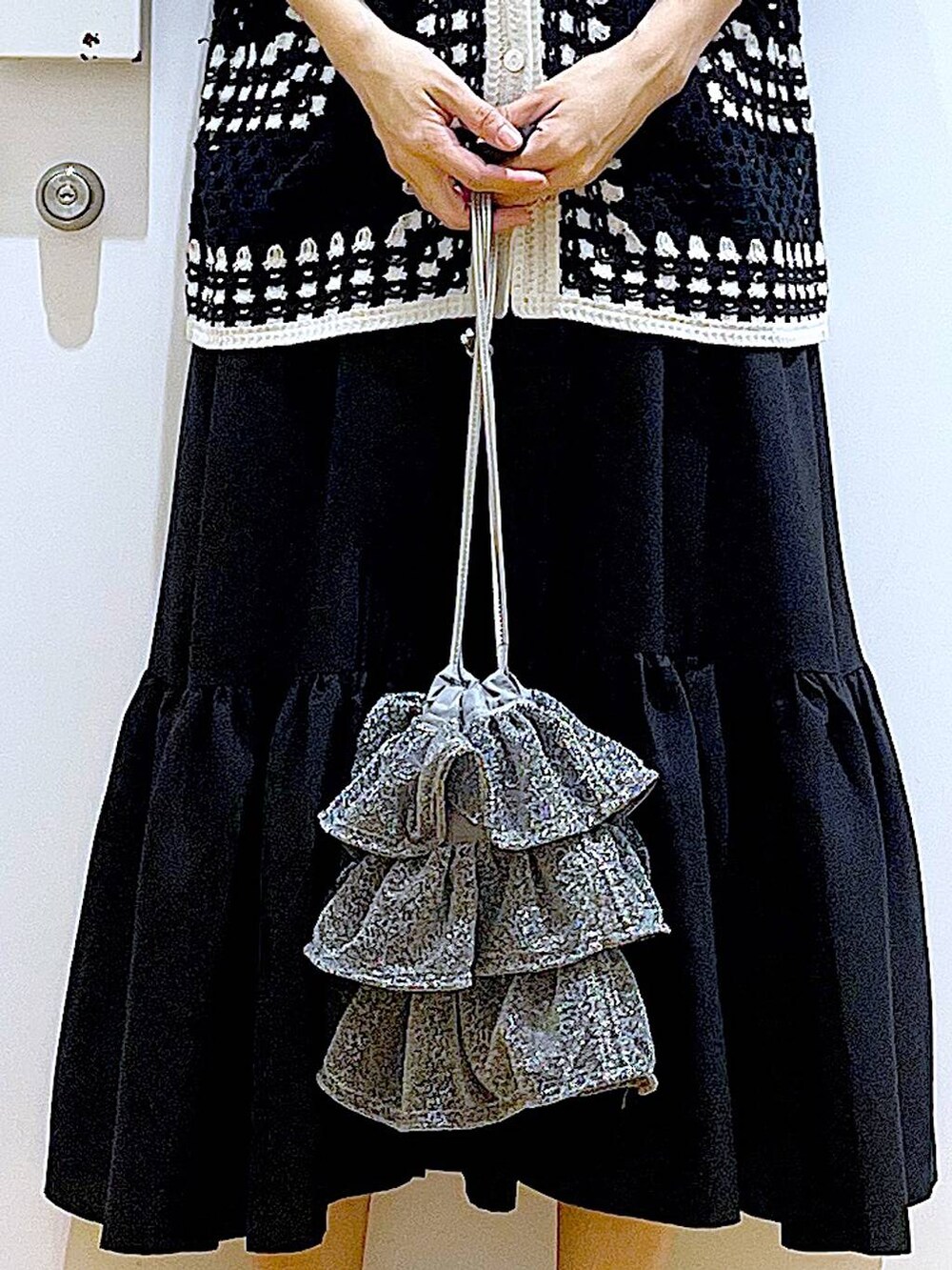 シルバー系のショルダーバッグ、ブラック系のパンプス、ブラック系のワンピースを着用したレディースの春コーディネートの9枚目の写真