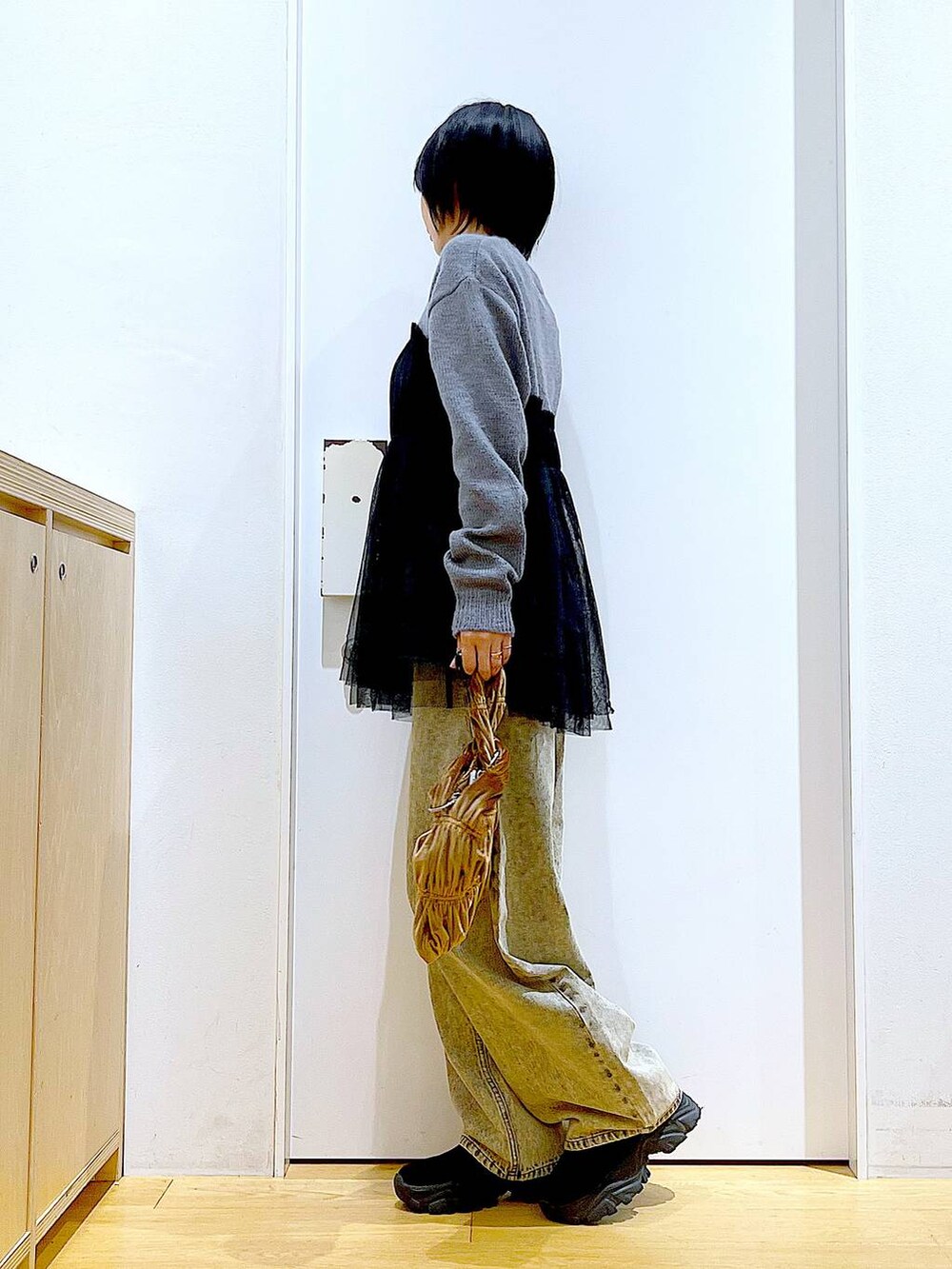 ブラック系のブーツ、イエロー系のショルダーバッグ、ベージュ系のデニムパンツを着用したレディースの秋コーディネートの3枚目の写真