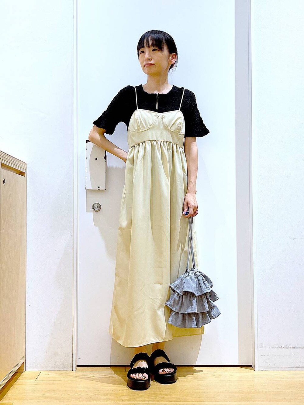 ブラック系のサンダル、イエロー系のワンピース、ブラック系のカーディガン/ボレロを着用したレディースの夏コーディネートの2枚目の写真