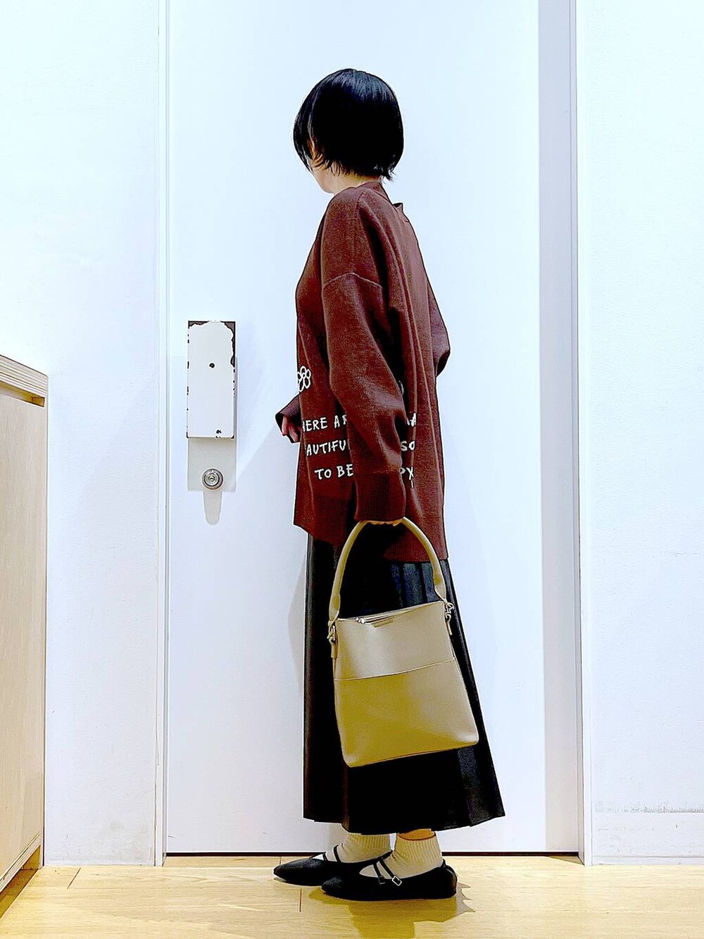 ブラック系のパンプス、ブラック系のスカート、ベージュ系のショルダーバッグを着用したレディースの秋コーディネートの3枚目の写真