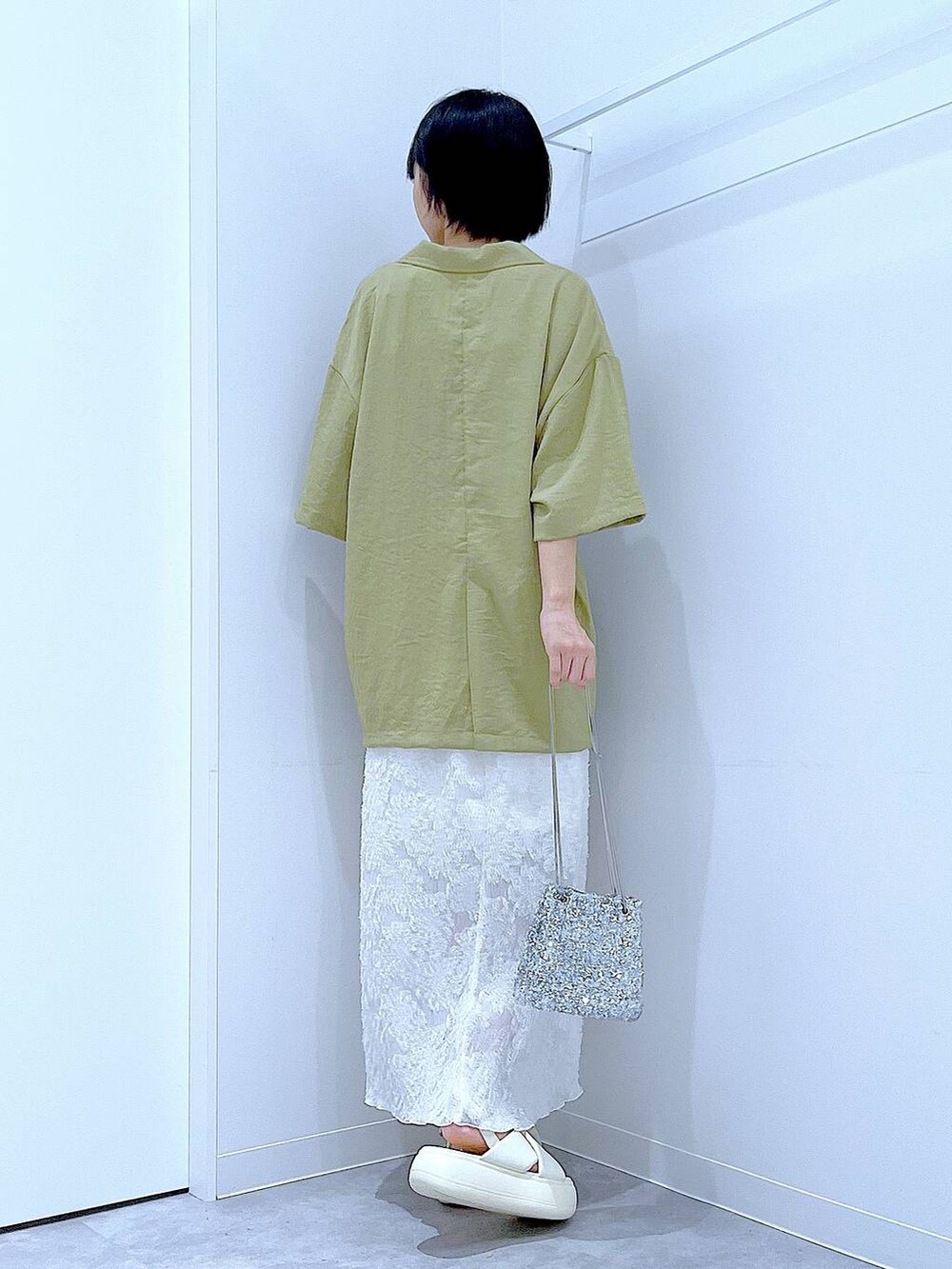 シルバー系のショルダーバッグ、ホワイト系のサンダル、グリーン系のテーラードジャケットを着用したレディースの夏コーディネートの5枚目の写真