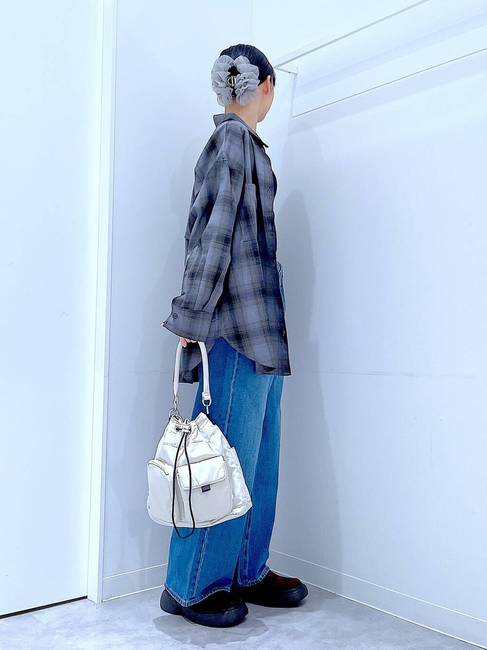 ブルー系のデニムパンツ、グレー系のシャツ/ブラウス、ホワイト系のハンドバッグを着用したレディースの秋コーディネートの4枚目の写真