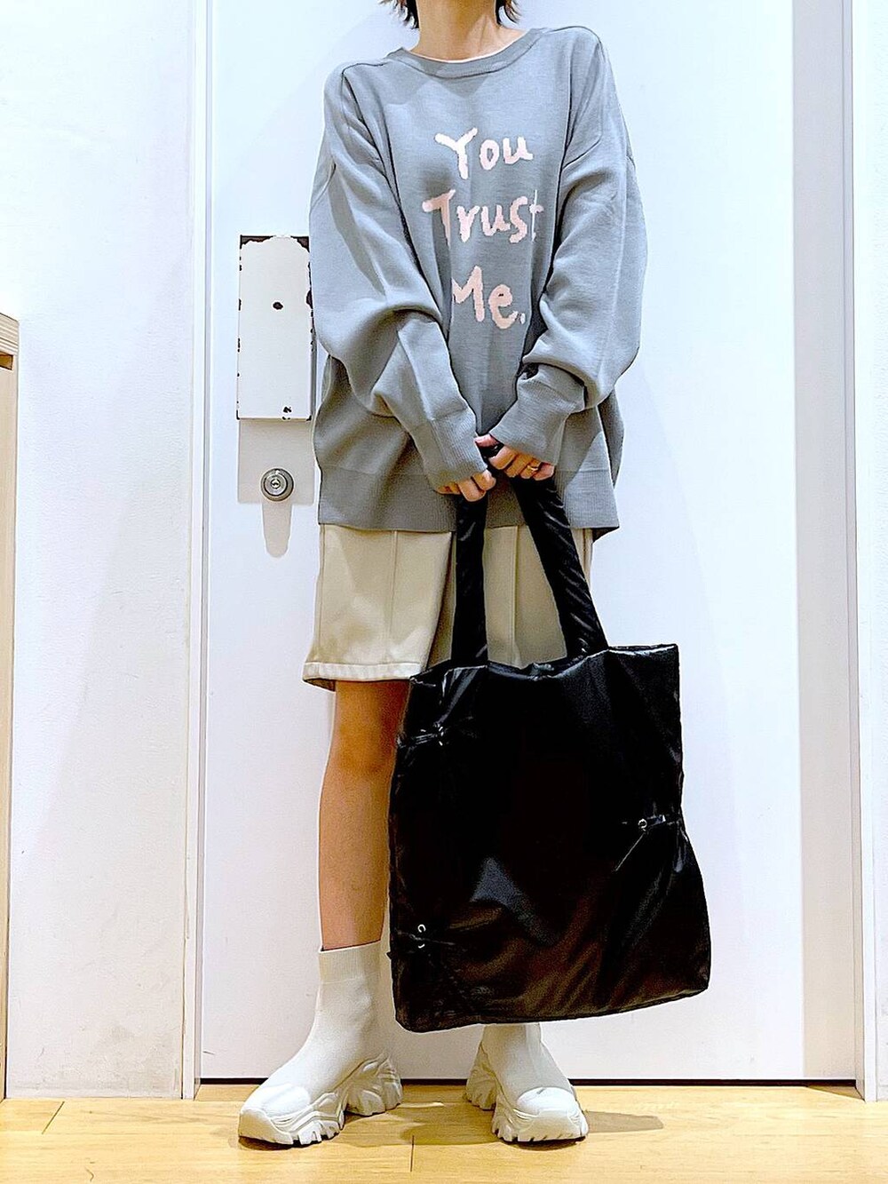 グレー系のニット/セーター、ブラック系のトートバッグ、ベージュ系のブーツを着用したレディースの冬コーディネートの6枚目の写真