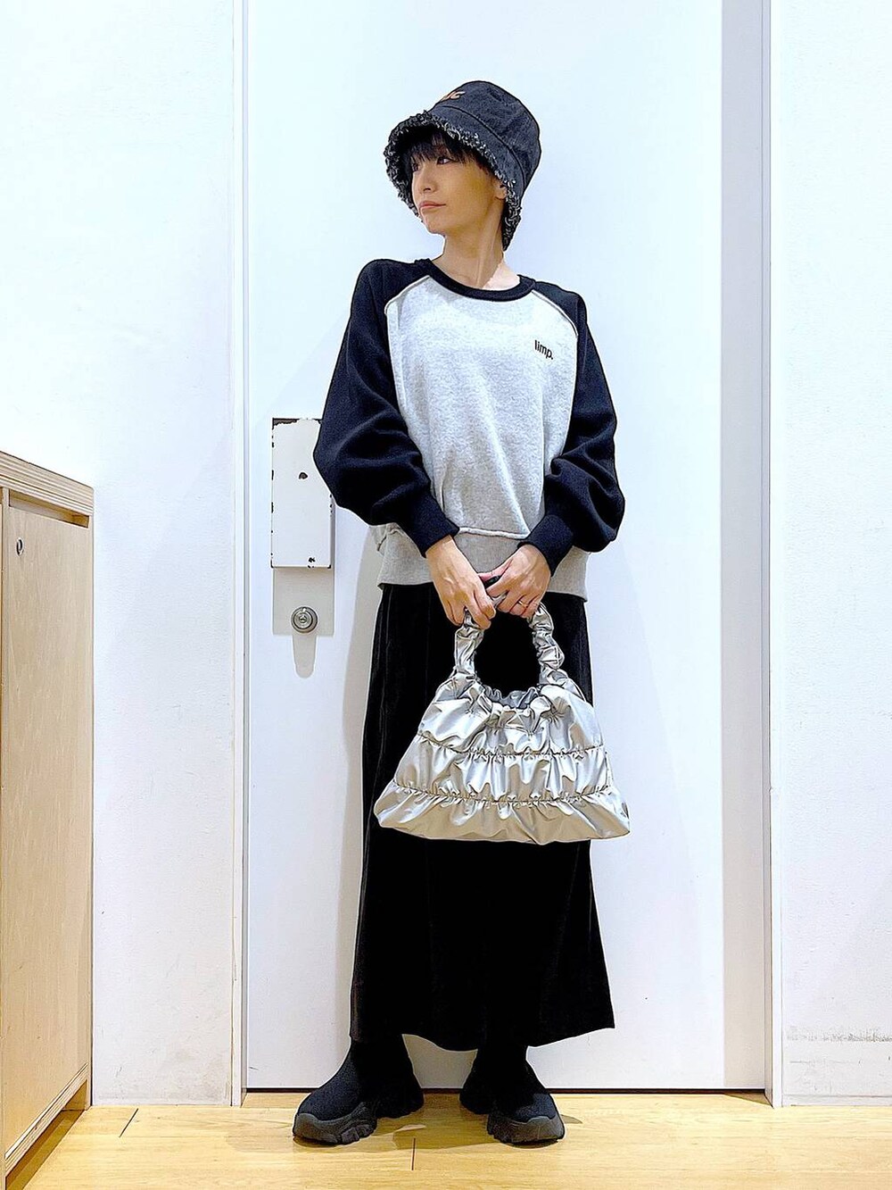 ブラック系のブーツ、シルバー系のショルダーバッグ、ブラック系のニット/セーターを着用したレディースの冬コーディネートの2枚目の写真