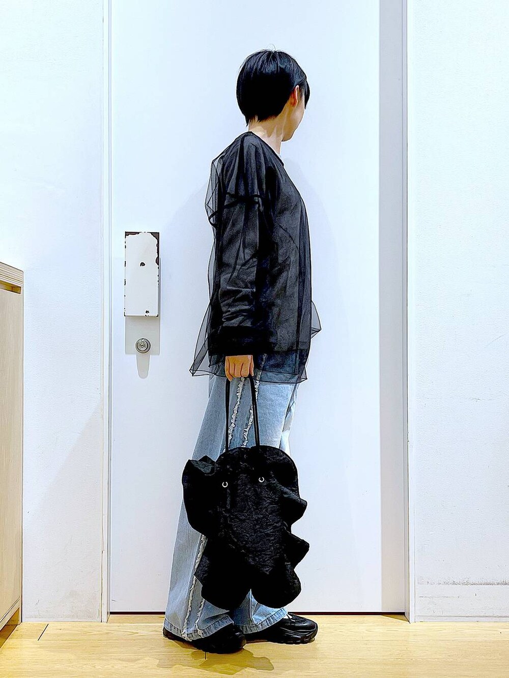 ブラック系のスニーカー、ブラック系のショルダーバッグ、ブルー系のデニムパンツを着用したレディースの春コーディネートの4枚目の写真