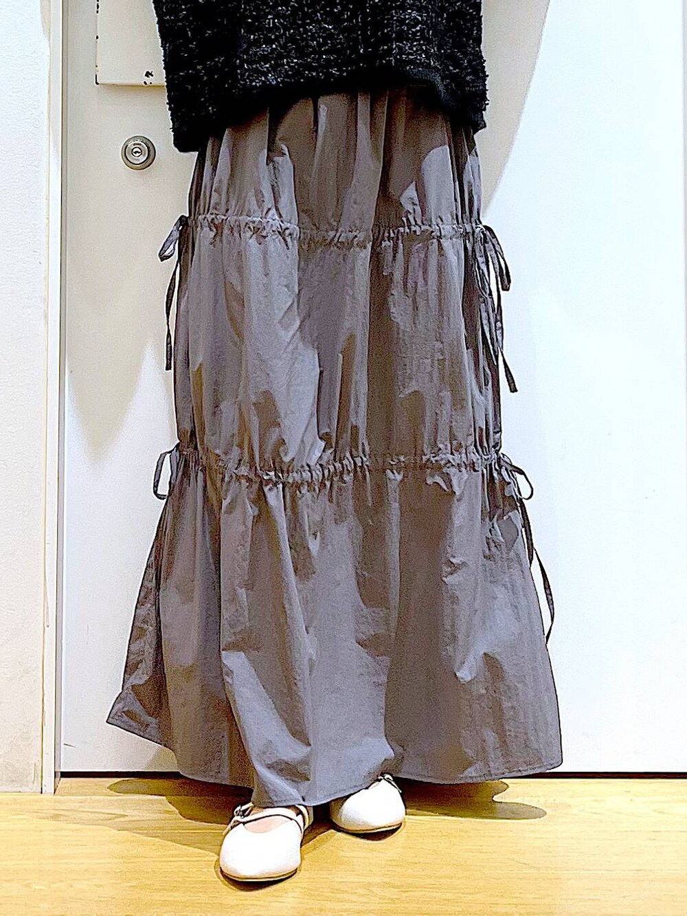 ブラック系のショルダーバッグ、ホワイト系のパンプス、グレー系のスカートを着用したレディースの秋コーディネートの8枚目の写真