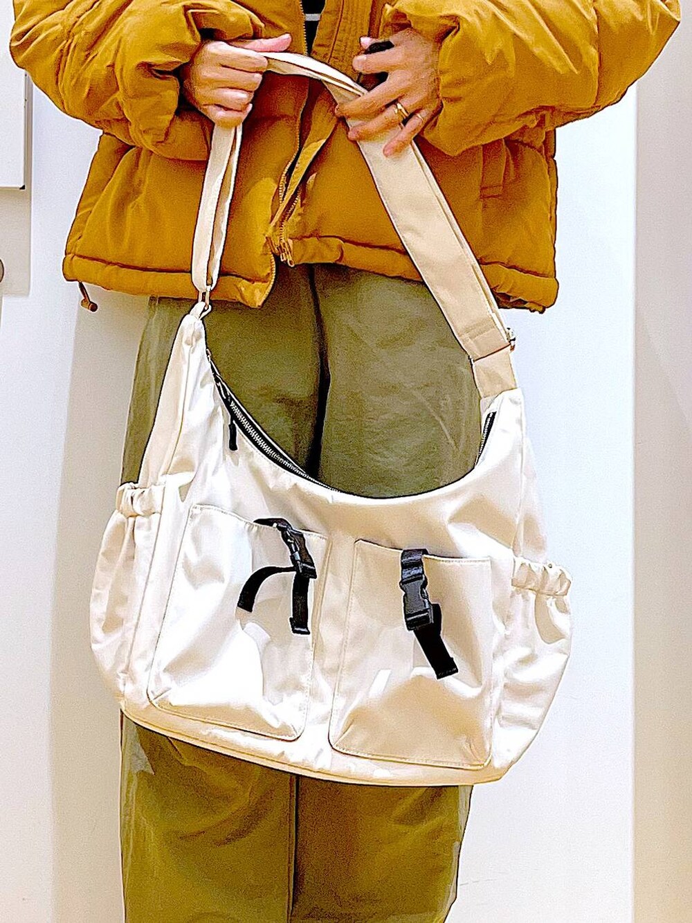 ゴールド系のナイロンジャケット、ベージュ系のブーツ、ブルー系のニット/セーターを着用したレディースの冬コーディネートの9枚目の写真