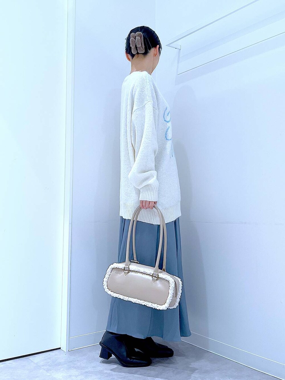 ブラック系のブーツ、ブルー系のスカート、ベージュ系のボストンバッグを着用したレディースの冬コーディネートの4枚目の写真