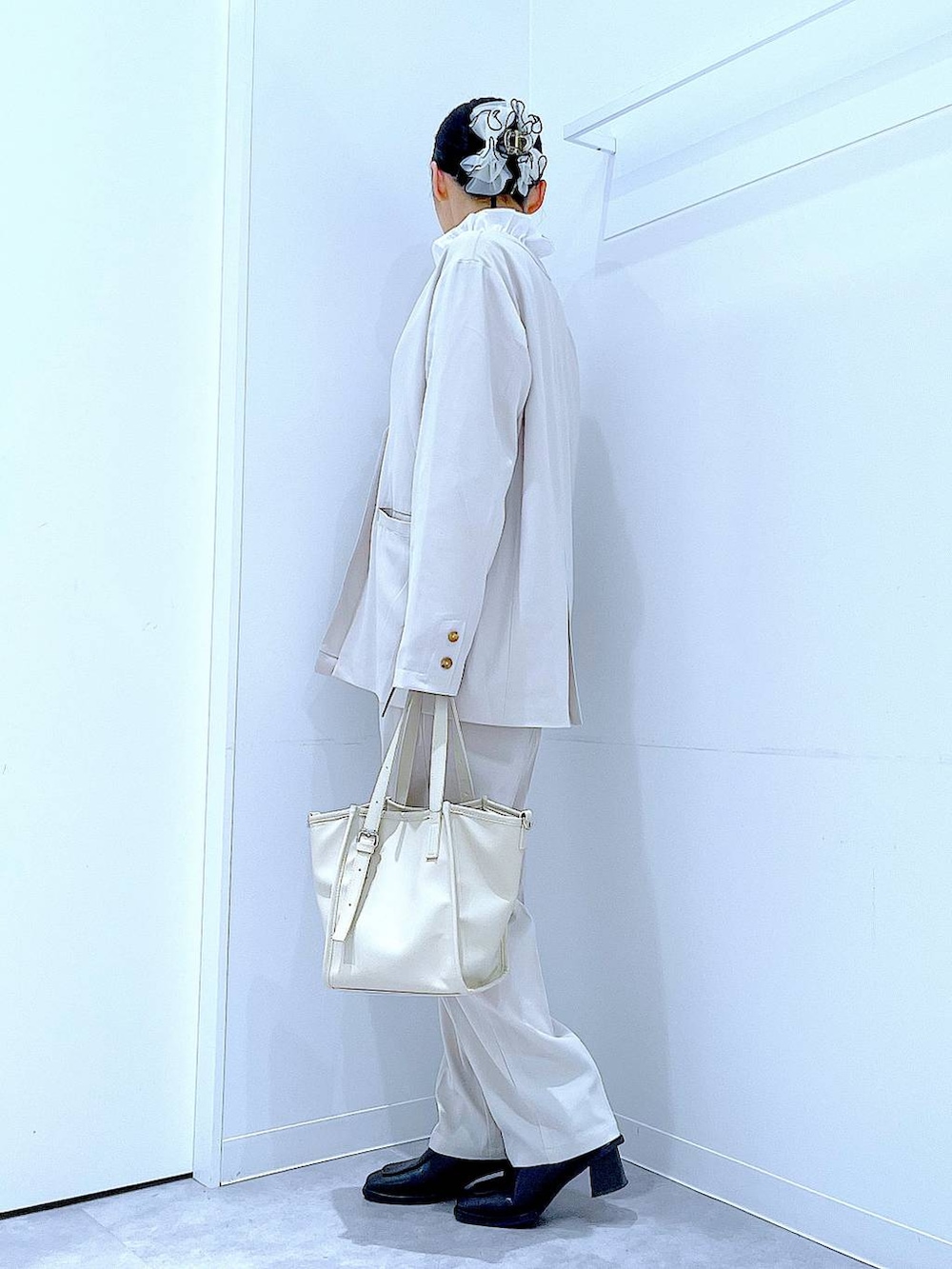 ブラック系のブーツ、ホワイト系のトートバッグ、ベージュ系のノーカラージャケットを着用したレディースの冬コーディネートの3枚目の写真