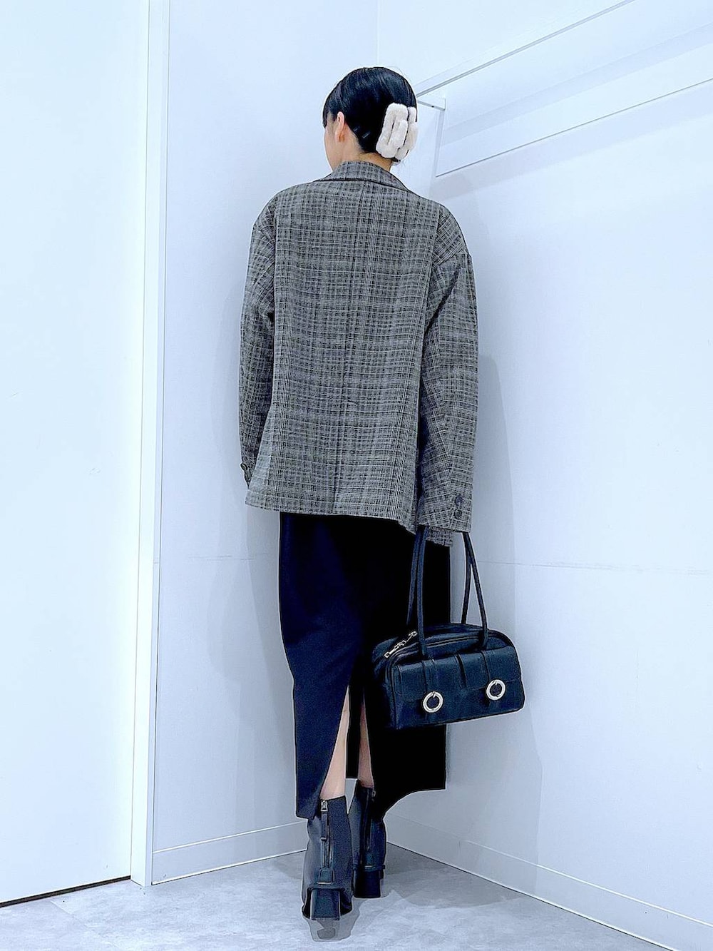 ブラック系のショルダーバッグ、ブラック系のスカート、ブラック系のブーツを着用したレディースの冬コーディネートの5枚目の写真