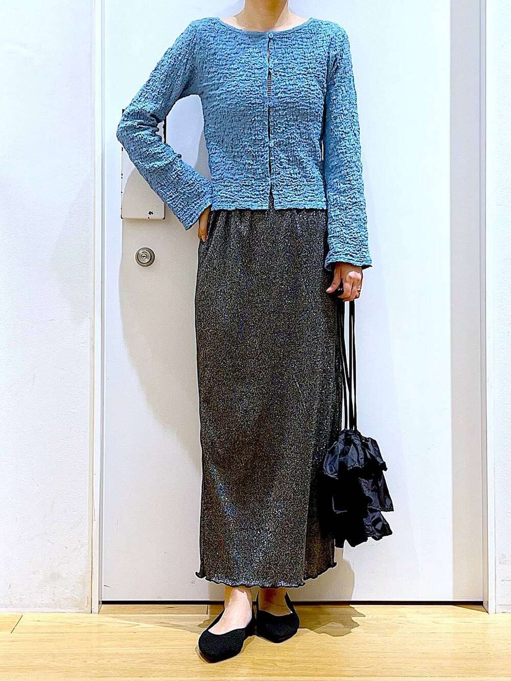 ブラック系のスカート、ブラック系のショルダーバッグ、ブラック系のパンプスを着用したレディースの春コーディネートの6枚目の写真