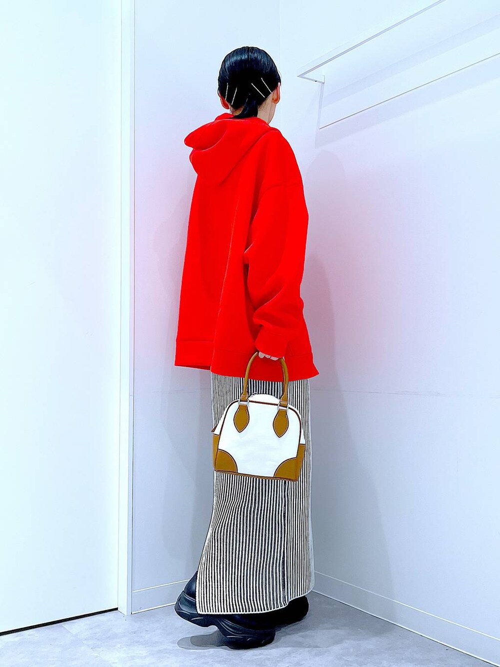 ブラック系のブーツ、ベージュ系のスカート、ホワイト系のハンドバッグを着用したレディースの秋コーディネートの4枚目の写真