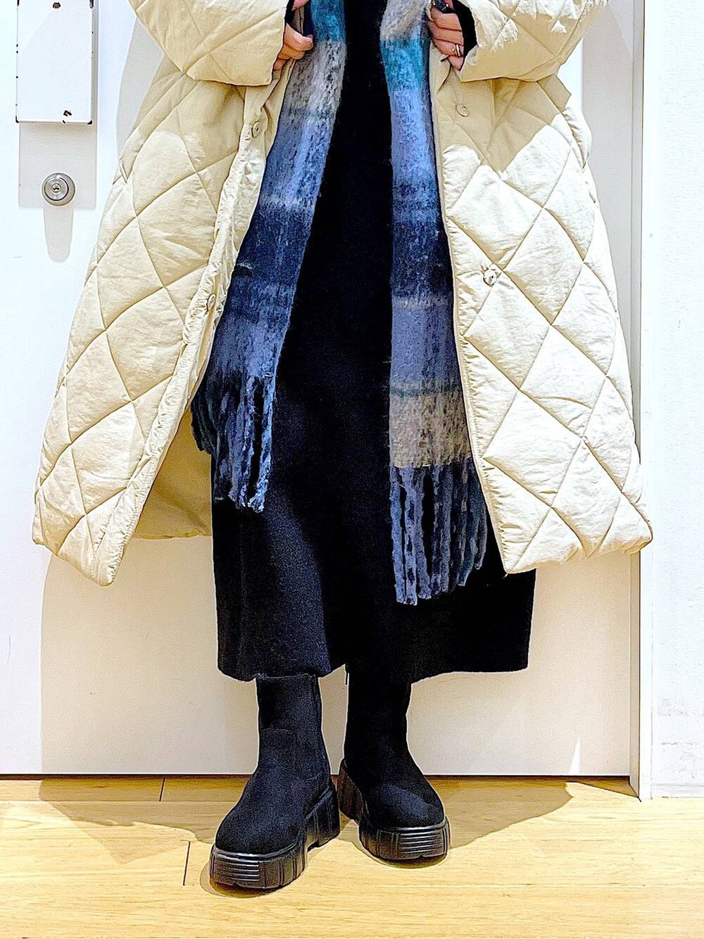 ブラック系のショルダーバッグ、ブラック系のブーツ、ベージュ系のノーカラーコートを着用したレディースの冬コーディネートの8枚目の写真