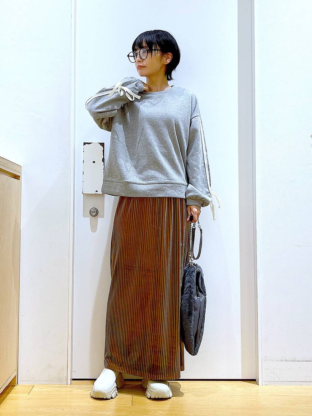 グレー系のショルダーバッグ、ブラウン系のスカート、ベージュ系のブーツを着用したレディースの秋コーディネートの2枚目の写真