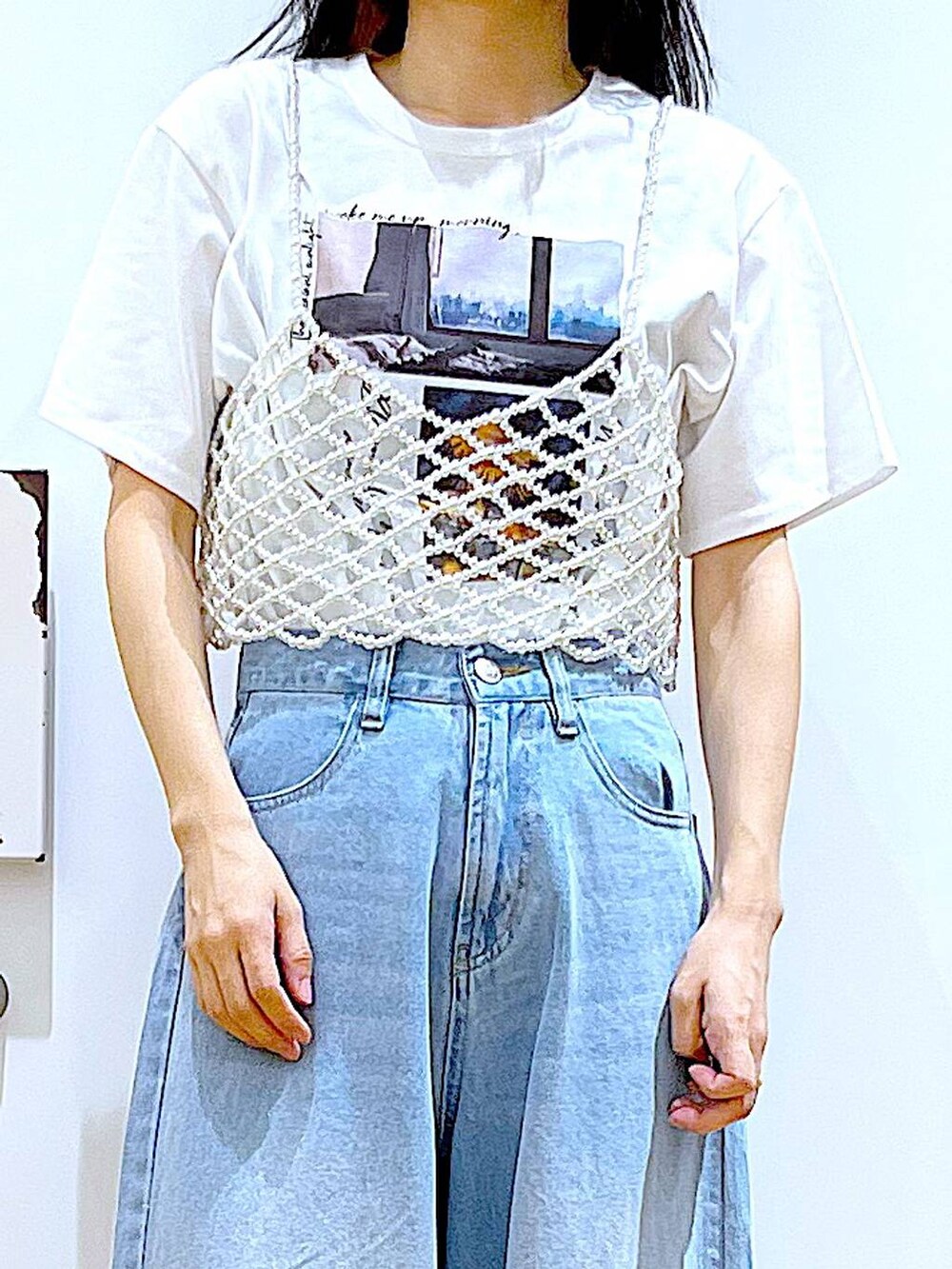 シルバー系のショルダーバッグ、ベージュ系のサンダル、ブルー系のデニムパンツを着用したレディースの夏コーディネートの7枚目の写真