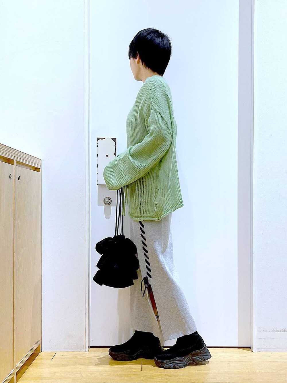 ブラック系のブーツ、グリーン系のニット/セーター、グレー系のスカートを着用したレディースの冬コーディネートの3枚目の写真