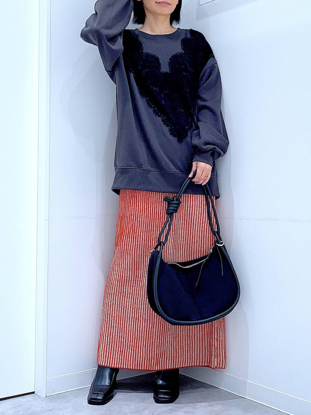 オレンジ系のスカート、ブラック系のブーツ、ブラック系のショルダーバッグを着用したレディースの秋コーディネートの6枚目の写真