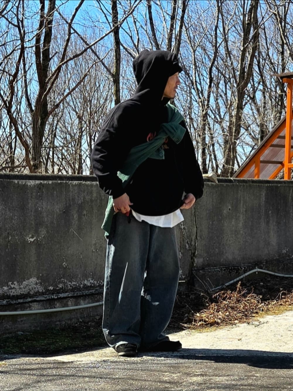 ブラック系のモカシン/デッキシューズ、ブルー系のデニムパンツ、グリーン系のカーディガン/ボレロを着用したメンズの春コーディネートの2枚目の写真