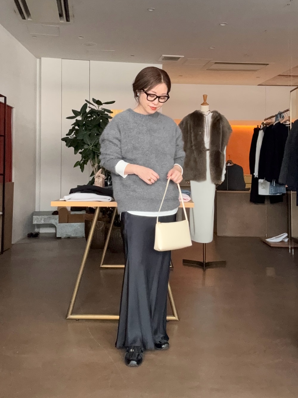 グレー系のニット/セーター、ホワイト系のシャツ/ブラウス、ブラック系のスカートを着用したレディースの秋コーディネートの2枚目の写真