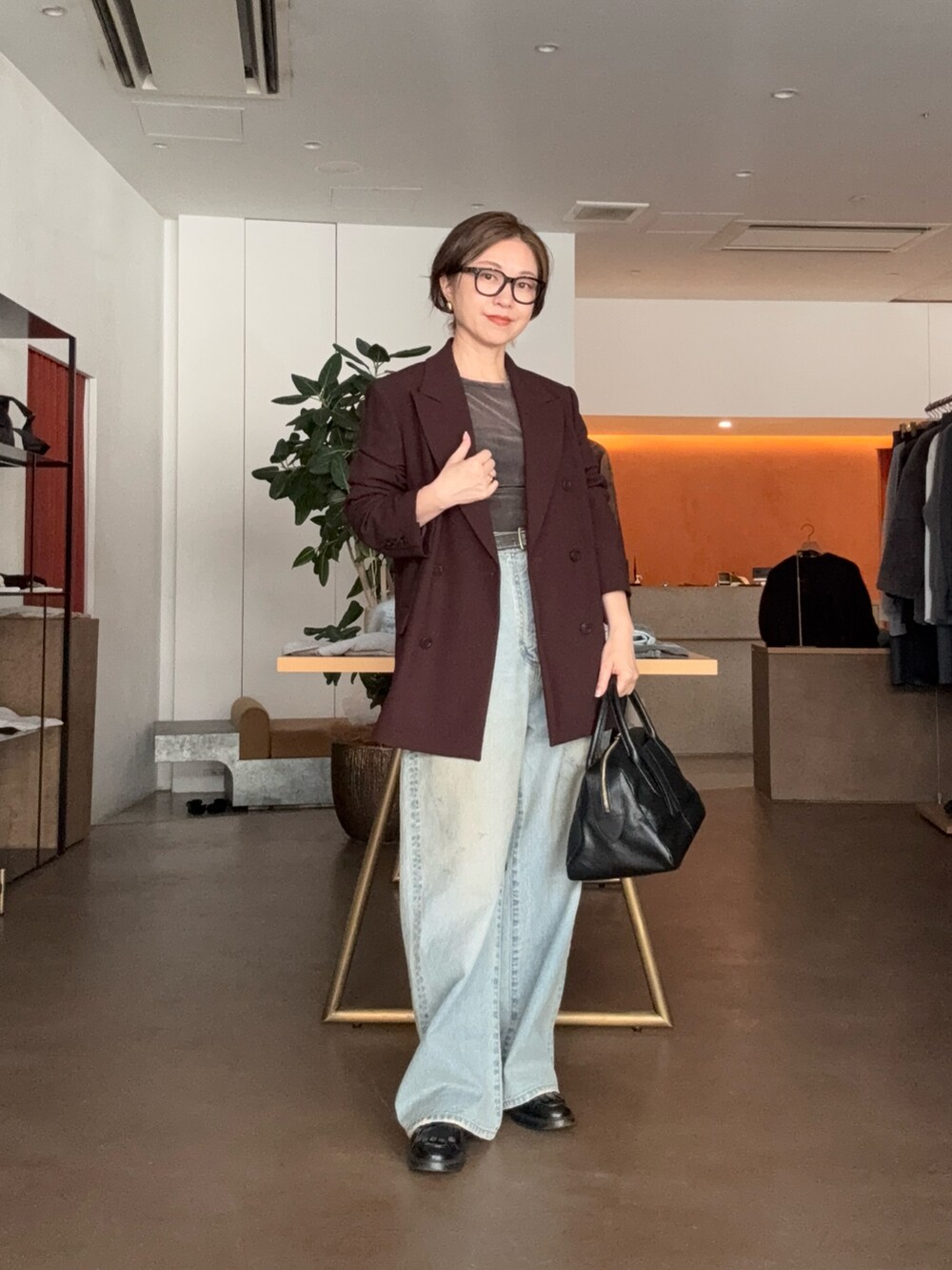 ブルー系のデニムパンツ、ブラック系のトートバッグ、ブラウン系のテーラードジャケットを着用したレディースの秋コーディネートの3枚目の写真