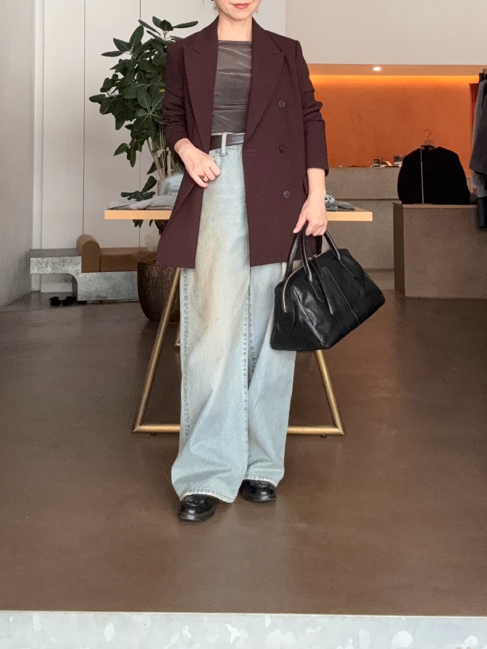 ブルー系のデニムパンツ、ブラック系のトートバッグ、ブラウン系のテーラードジャケットを着用したレディースの秋コーディネートの4枚目の写真