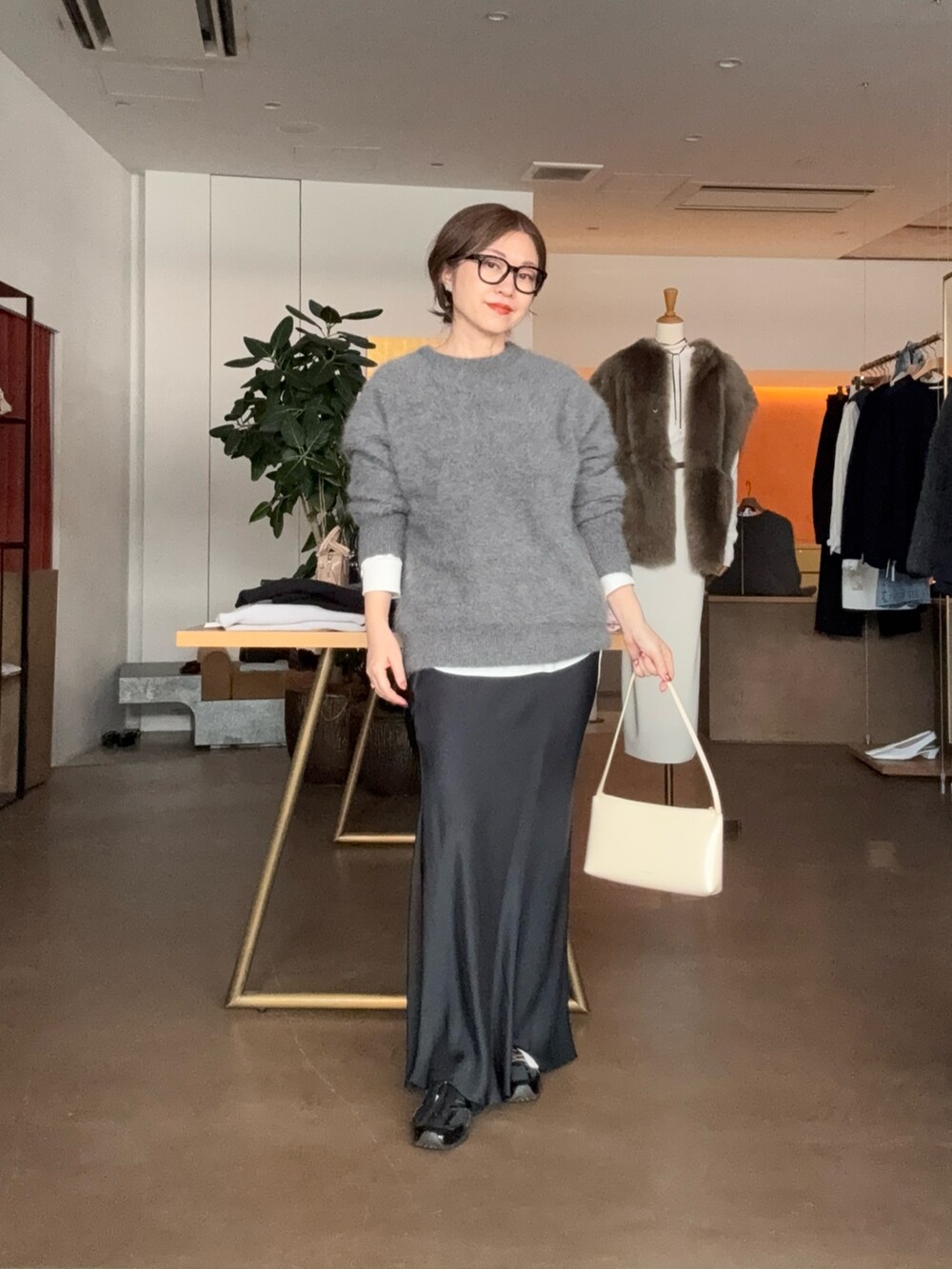 グレー系のニット/セーター、ホワイト系のシャツ/ブラウス、ブラック系のスカートを着用したレディースの秋コーディネートの3枚目の写真