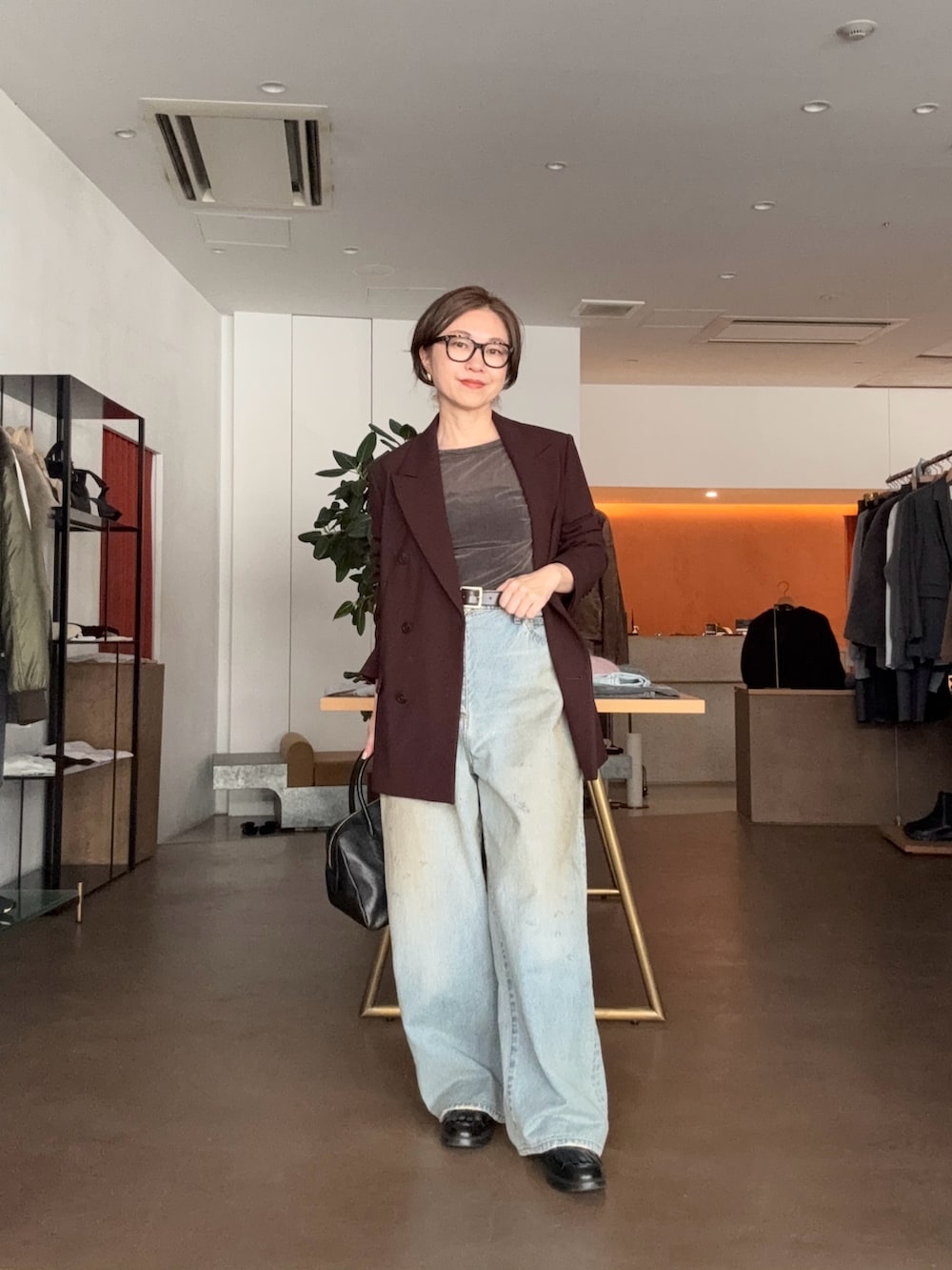 ブルー系のデニムパンツ、ブラック系のトートバッグ、ブラウン系のテーラードジャケットを着用したレディースの秋コーディネートの2枚目の写真