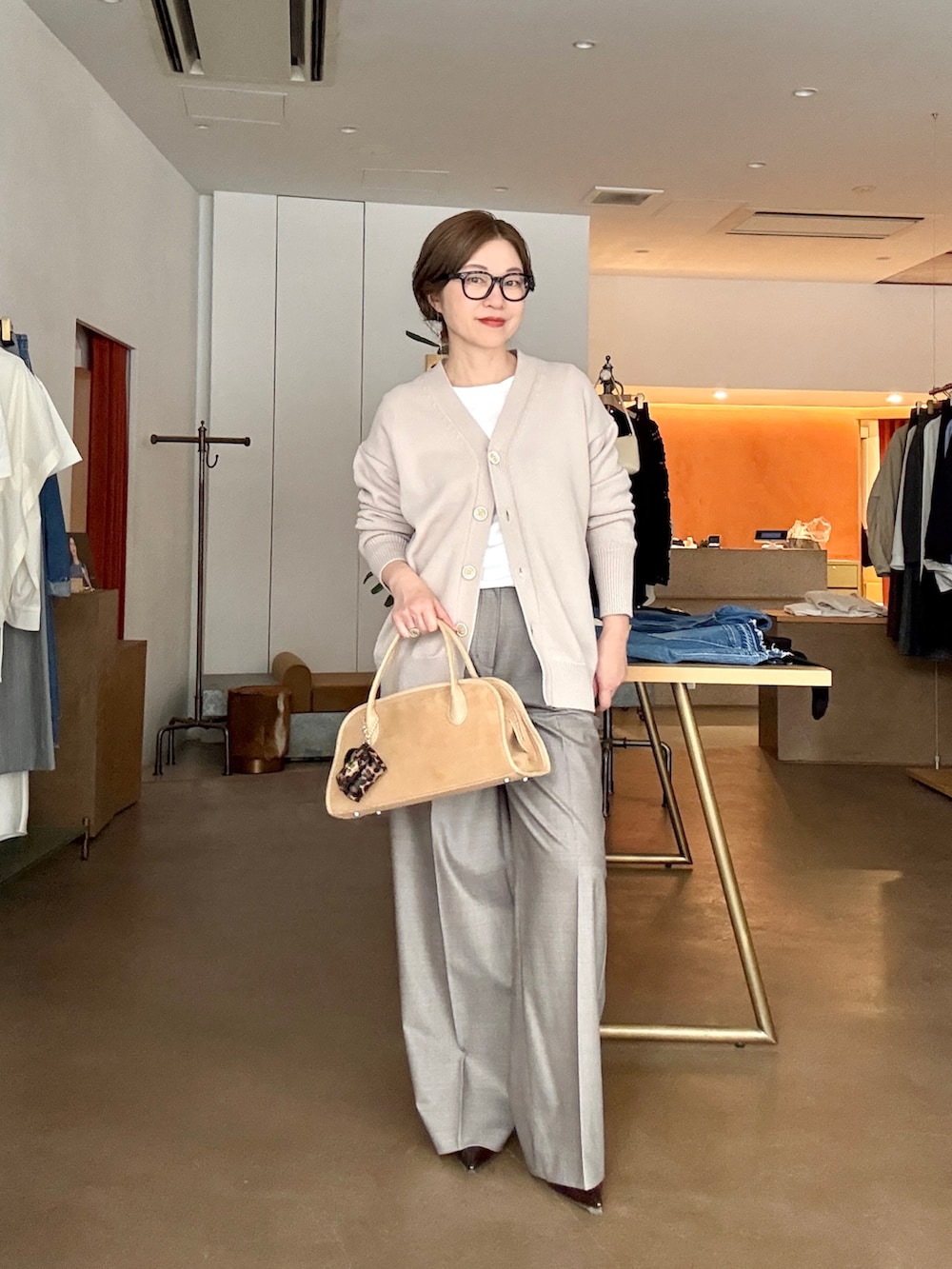 ベージュ系のカーディガン/ボレロ、ホワイト系のTシャツ/カットソー、ブラウン系のスラックスを着用したレディースの冬コーディネートの3枚目の写真