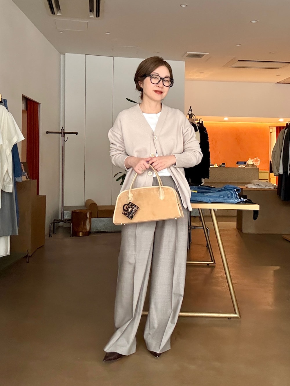 ベージュ系のカーディガン/ボレロ、ホワイト系のTシャツ/カットソー、ブラウン系のスラックスを着用したレディースの冬コーディネートの5枚目の写真