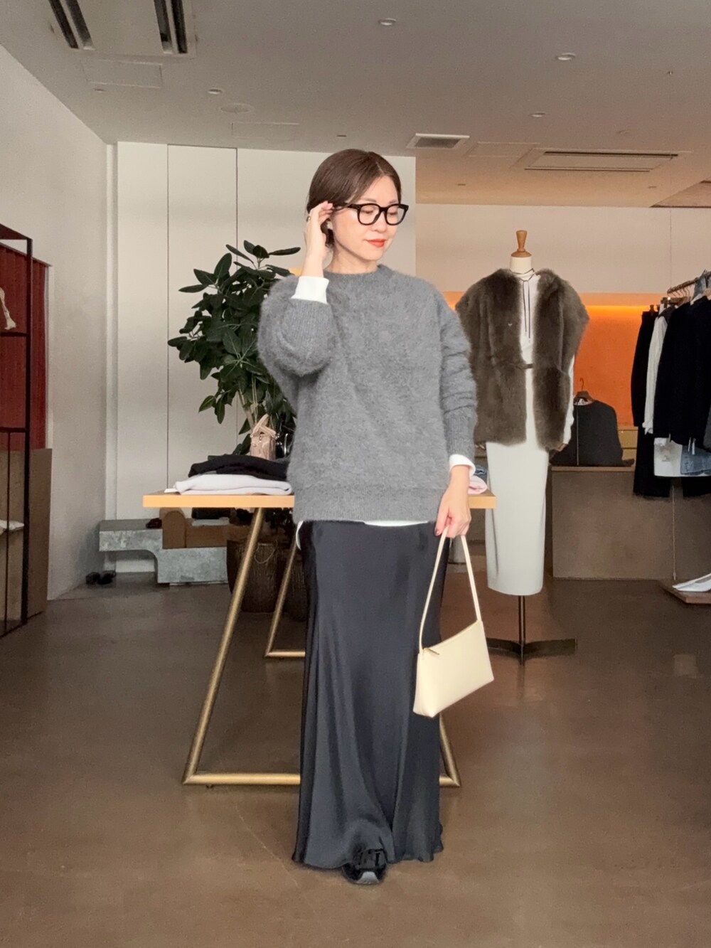 グレー系のニット/セーター、ホワイト系のシャツ/ブラウス、ブラック系のスカートを着用したレディースの秋コーディネートの4枚目の写真