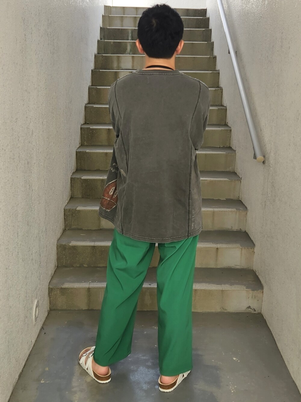 グリーン系のパンツ、ホワイト系のサンダル、ブラック系のTシャツ/カットソーを着用したメンズの秋コーディネートの2枚目の写真