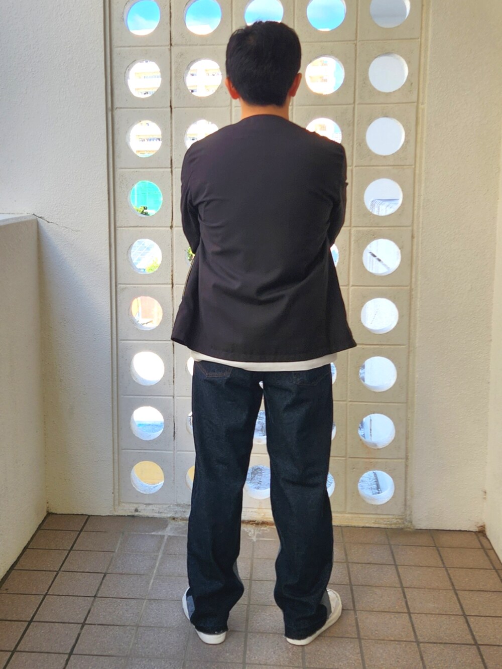 ブルー系のデニムパンツ、グレー系のTシャツ/カットソー、ホワイト系のスニーカーを着用したメンズの冬コーディネートの2枚目の写真
