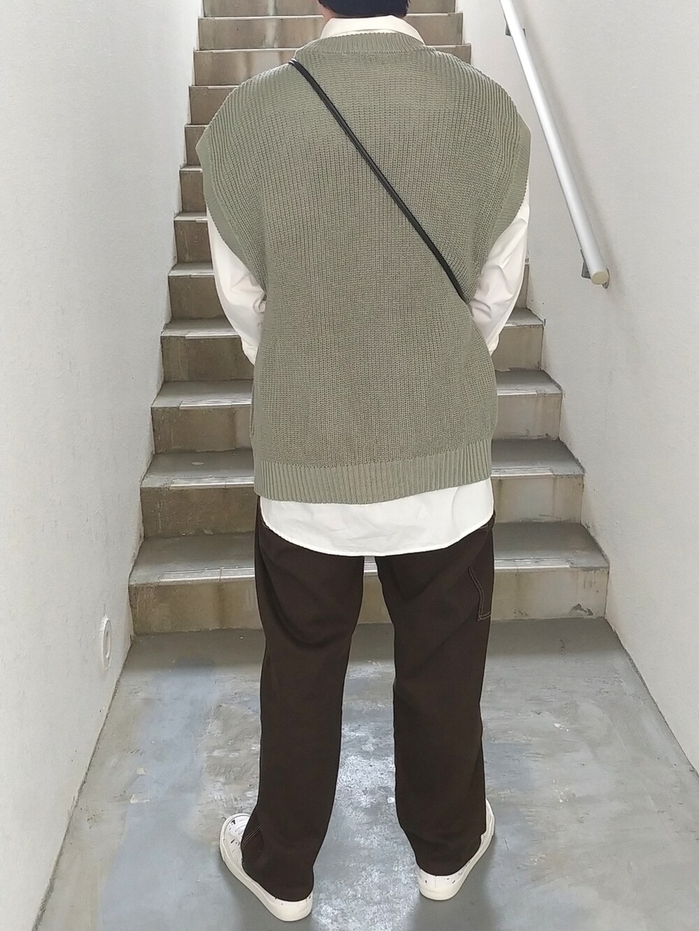 ブラウン系のその他パンツ、ホワイト系のスニーカー、グリーン系のニット/セーターを着用したメンズの春コーディネートの2枚目の写真